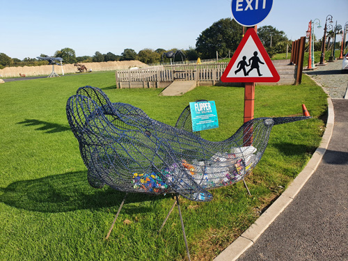 A powerful sculpture at the British Ironwork Centre illustrating the impact of sea pollution, featuring a marine scene filled with various pieces of discarded rubbish and debris.