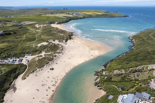 Experience the breathtaking view of Crantock Beach in Newquay, Cornwall. Enjoy golden sands, rolling waves, and picturesque dunes, set against the backdrop of rugged coastal cliffs and tranquil natural beauty