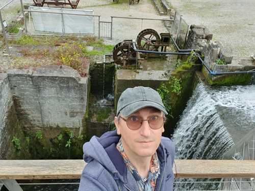 Explore Cromford Mills and enjoy the serene sight of visitors admiring the beautiful waterfall. Discover the historic mill complex, rich industrial heritage, and scenic views in a charming setting.