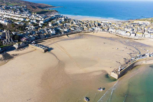 A serene photo of the sandy shores of a harbor in Cornwall, capturing the tranquil beauty and coastal charm of the area. The image highlights the soft textures of the sand and the peaceful atmosphere of the harbor, making it ideal for beach lovers, coastal enthusiasts, and travel photography