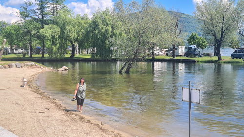 woman walking along a sandy beach next to a lake Maggiore
