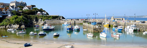 Experience the scenic view of Newquay Harbour in Cornwall, where colorful boats, historic buildings, and bustling maritime activity come together. Ideal for enjoying the charm and vibrancy of this coastal port.
