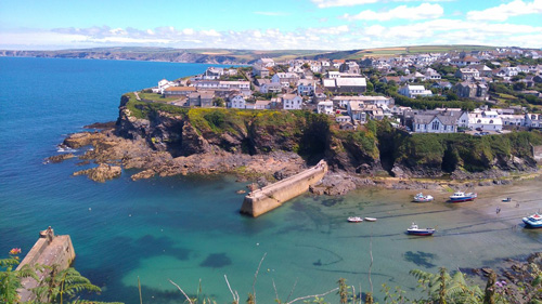 Enjoy breathtaking views over the bay in Port Isaac, a picturesque Cornish village. Admire the stunning coastal scenery, historic harbor, and charming village nestled against the rugged cliffs.