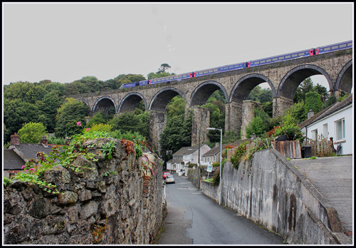 Admire the impressive view of St. Austell Viaduct in Cornwall. This historic railway structure offers a stunning architectural sight, with its majestic arches spanning the scenic landscape and providing a striking contrast against the natural surroundings