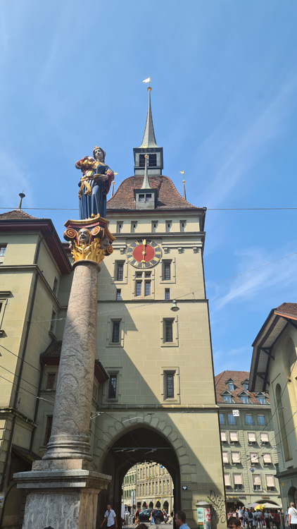 Käfigturm Clock Tower with medieval architecture, turrets, and a crowning statue, set against a clear sky with clouds