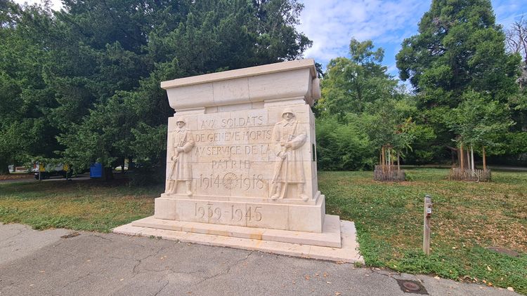 Stone monument with a statue honoring Geneva's soldiers who died between 1945 and 1959, surrounded by trees and grass
