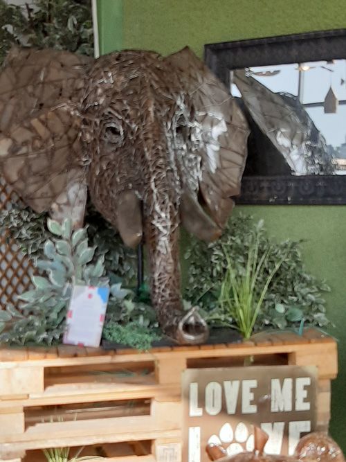A striking metal sculpture of an elephant head inside a building at the British Ironwork Centre, showcasing intricate details and craftsmanship.