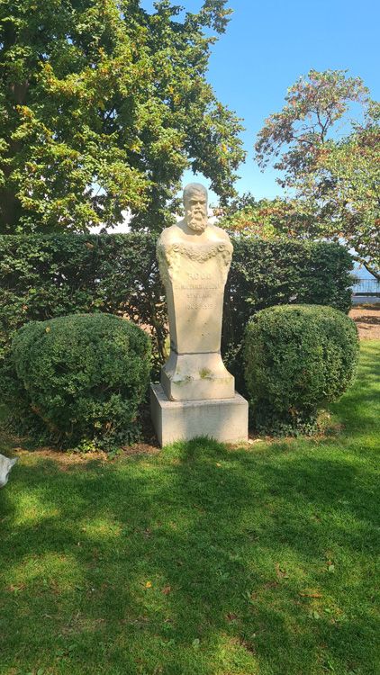 Statue in a grassy area with surrounding trees and plants in Parc des Bastions, Geneva