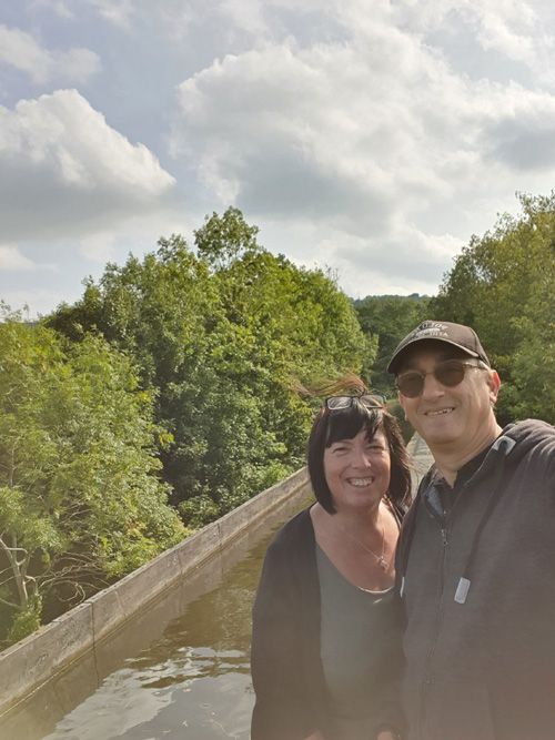 wo individuals sharing a quiet moment on Pontcysyllte Aqueduct, with the historic canal and countryside stretching into the distance under a serene sky