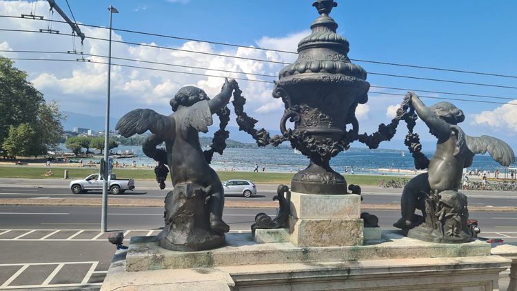 A statue of a man and woman holding hands outdoors near the History of Science Museum in Geneva, surrounded by urban elements