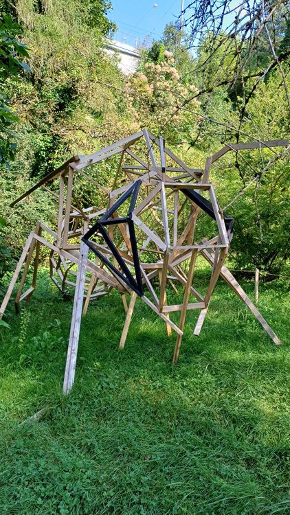 Large bee sculpture in the Universität Bern Botanical Garden, surrounded by greenery