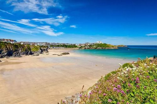 Enjoy a stunning view from Great Western Beach in Newquay, Cornwall. Admire the expansive golden sands, rolling waves, and scenic coastal cliffs of this popular beach destination.